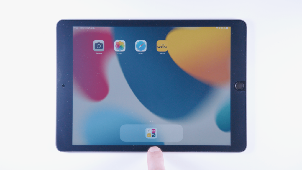 iPad: Ein Finger tippt auf auf den untersten Rand des iPads.