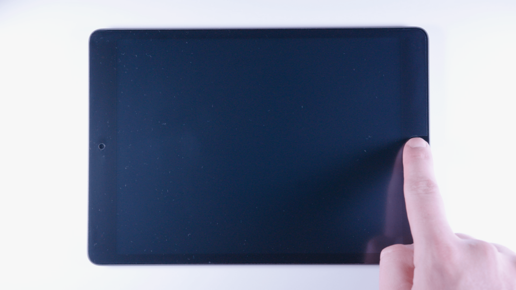 iPad: Bildschirm ist aus. Ein Finger drückt auf den Homebutton.