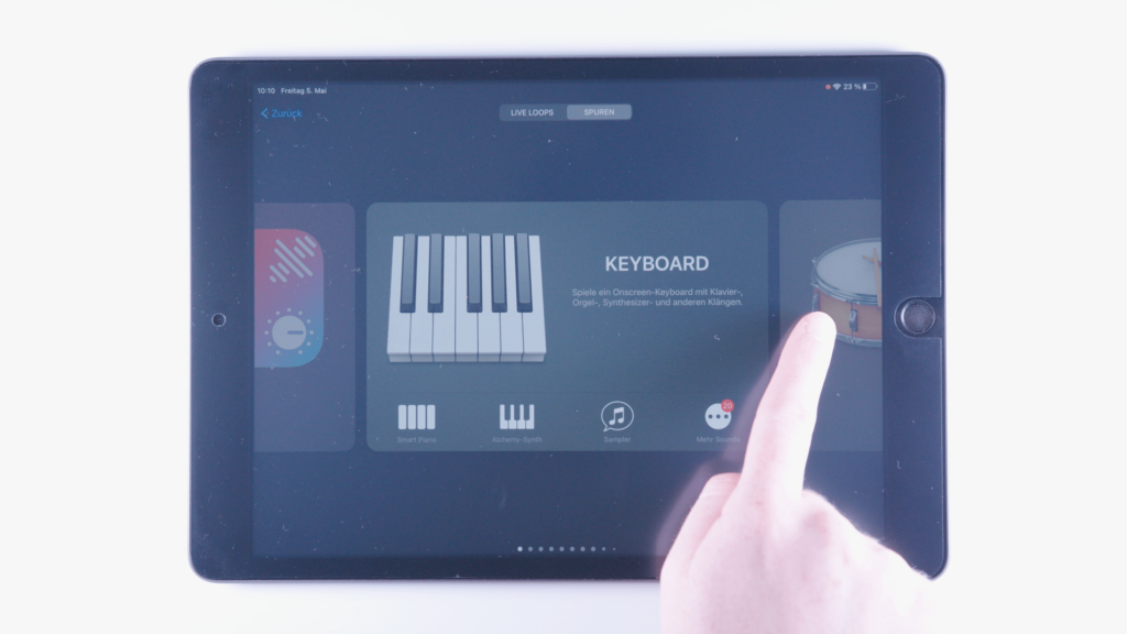 (iPad:) GarageBand geöffnet: Sound-Übersicht zeigt Klavier/Keyboard (bildschirmfüllend) Zeigefinger am rechten Bildschirmrand