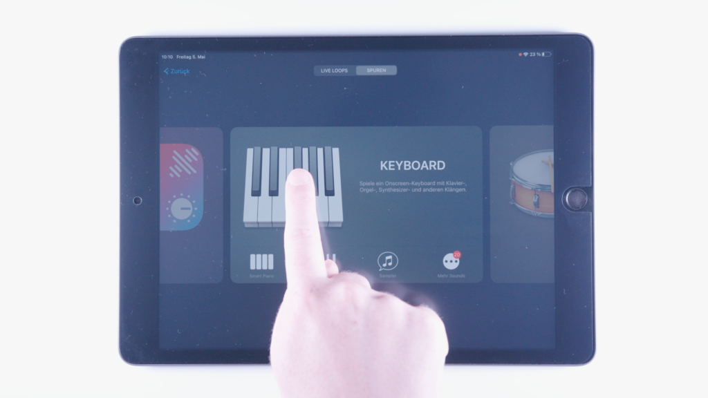 (iPad:) GarageBand geöffnet: Sound-Übersicht zeigt Klavier/Keyboard (bildschirmfüllend) Zeigefinger in der Bildschirmmitte