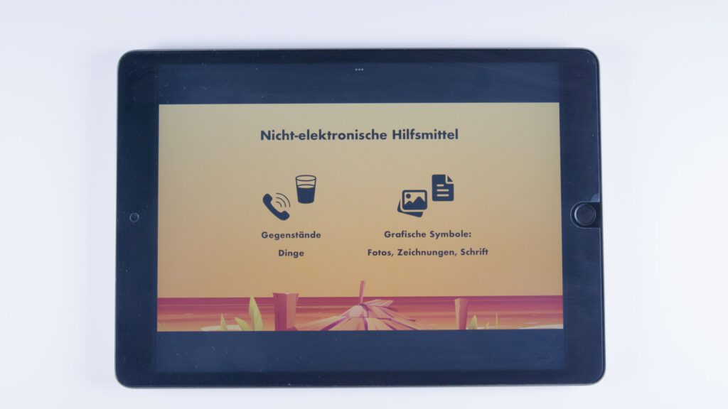 Tablet mit orangem Hintergrund. Überschrift: „Nicht-elektronische Hilfsmittel“. Zwei Gruppen: Links ein Telefonhörer und ein Trinkglas mit dem Text „Gegenstände, Dinge“, rechts zwei Symbole für Bilder und Dokumente mit dem Text „Grafische Symbole: Fotos, Zeichnungen, Schrift“.