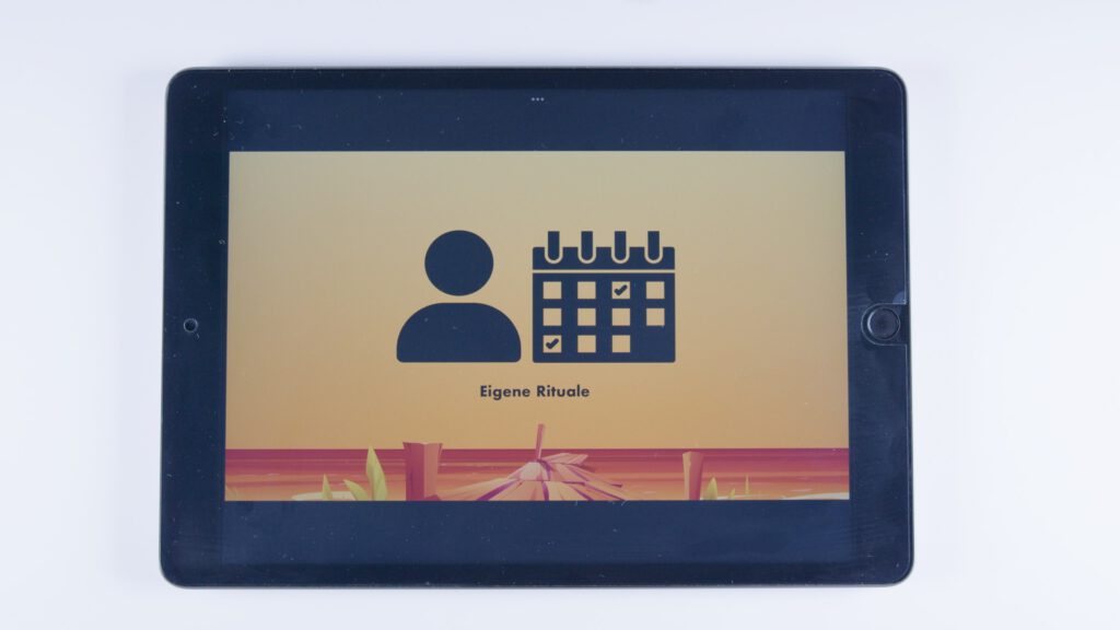 Tablet mit orangem Hintergrund. Links ein Symbol für eine Person, rechts ein Kalender mit Häkchen. Darunter steht: „Eigene Rituale“.