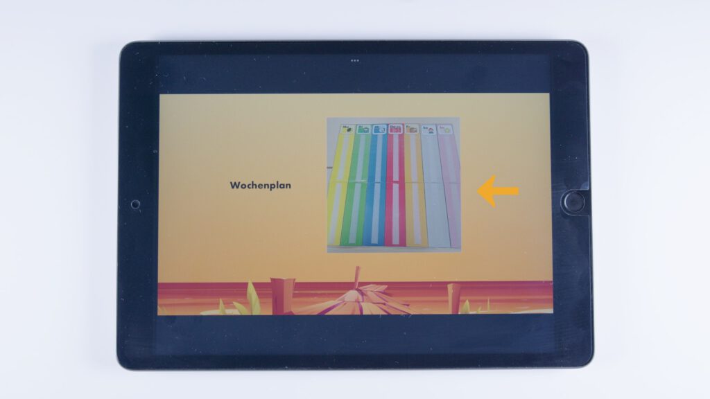 Tablet mit orangem Hintergrund. In der Mitte ein Foto eines farblich sortierten Wochenplans mit Symbolen für Wochentage. Links daneben steht „Wochenplan“, rechts zeigt ein gelber Pfeil auf das Bild.