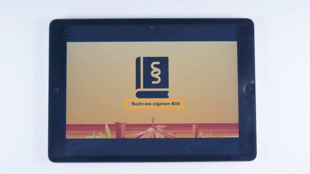 Tablet mit orangem Hintergrund. In der Mitte ein Symbol eines Gesetzbuchs mit Paragraphenzeichen, darunter ein orange hinterlegter Text: „Recht am eigenen Bild“.