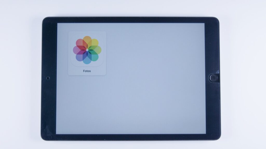 Tablet mit geöffneter Fotos-App auf hellem Hintergrund. Die App ist groß dargestellt und nimmt die obere linke Ecke ein.